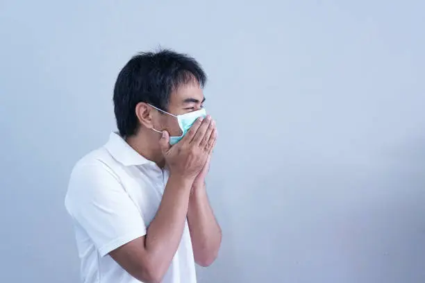 Asian Man in medical mask Coronavirus pandemic disease on grey background. COVID-19 virus from China epidemic outbreak to global recession concept for person social, air pollution, Respiratory illness