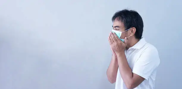 Asian Man in medical mask Coronavirus pandemic disease on grey background. COVID-19 virus from China epidemic outbreak to global recession concept for person social, air pollution, Respiratory illness