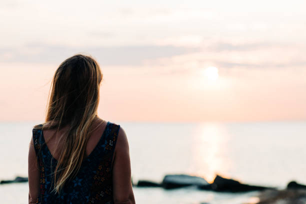 istock Young woman enjoying sunset on the beach 1213707438