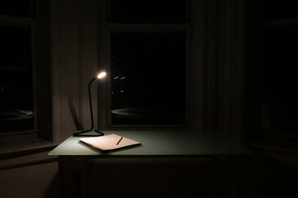 istock Home Desk at Night with a Light and Notebook with a Pencil 1213707748