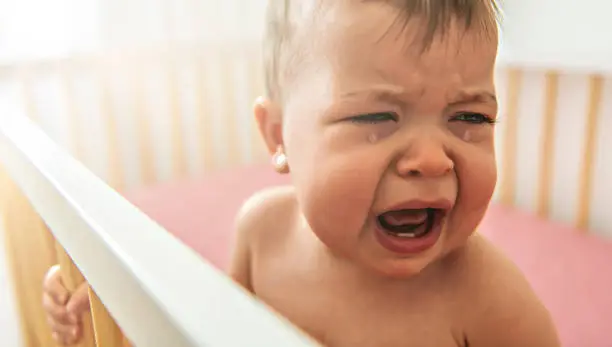Photo of The baby cries and calls mum from a bed