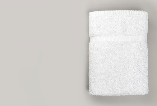 Top view of Fluffy clean white bathroom towel on gray background with copy space