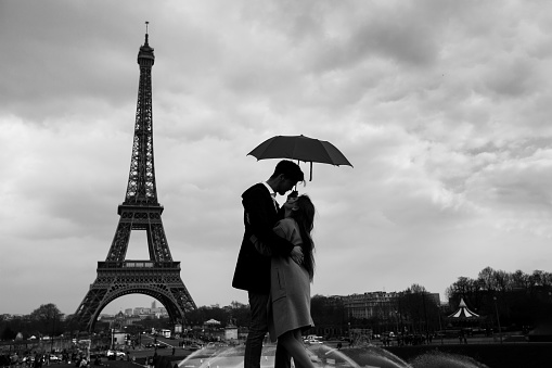 retro view of Paris, couple under umbrella near Eiffel tower, vintage