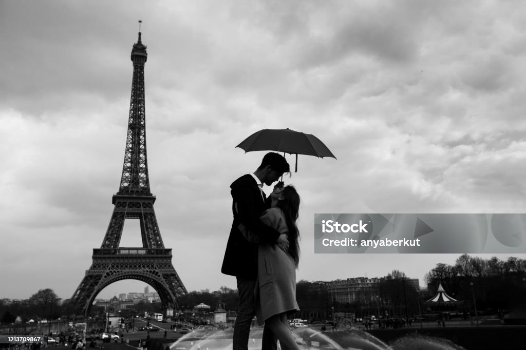 retro view of Paris, couple under umbrella near Eiffel tower, vintage retro view of Paris, couple under umbrella near Eiffel tower, vintage black and white monochrome Retro Style Stock Photo