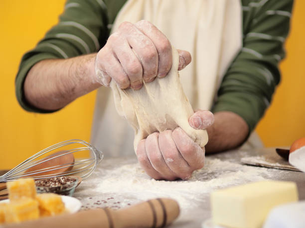 male hands kneading dough on wooden table