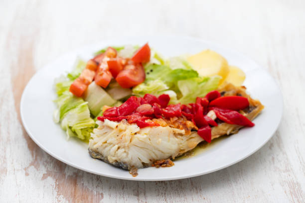 istock cod fish with red pepper, potato and salad on white plate on ceramic background 1213715918