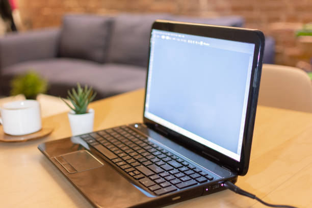istock Laptop computer with blank screen and a cup of coffee on table at home interior in the evening. 1213717800