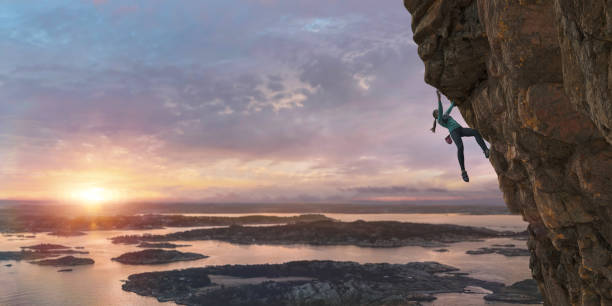 scalatrice libera femminile che scala la ripida parete rocciosa costiera all'alba - land sale foto e immagini stock