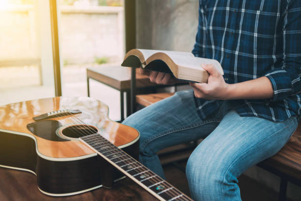 istock a man hands holding  and read book  with guitar on wooden table, 1213722884