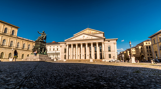 Munich 2019. Long exposure of tourists passing in front of the Bavarian National Theater located on Max-Joseph-Platz. We are in the afternoon of a warm and sunny summer day. August 2019 in Munich.