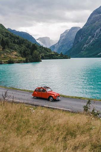 Red vintage car on the road near the fjord in Norway