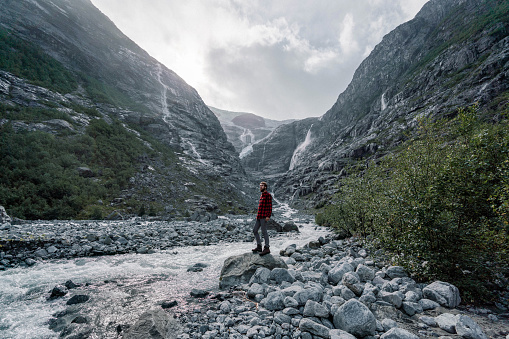 Young Caucasian man in red shirt  walking to the glacier in Norway