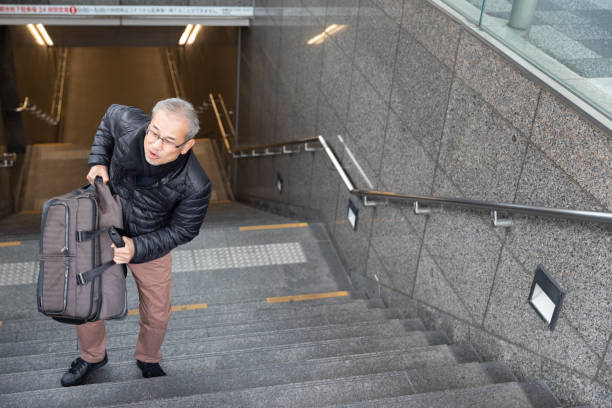 istock Senior man walking up the stairs with suitcase 1213730287
