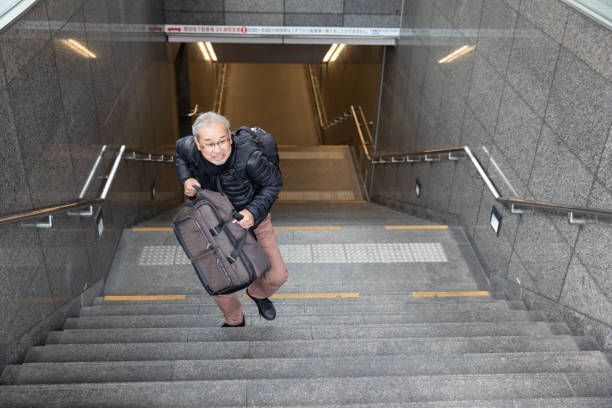 istock Senior man walking up the stairs with suitcase 1213731336