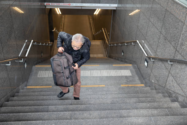 istock Senior man walking up the stairs with suitcase 1213731456