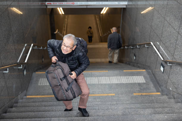 istock Senior man walking up the stairs with suitcase 1213731671