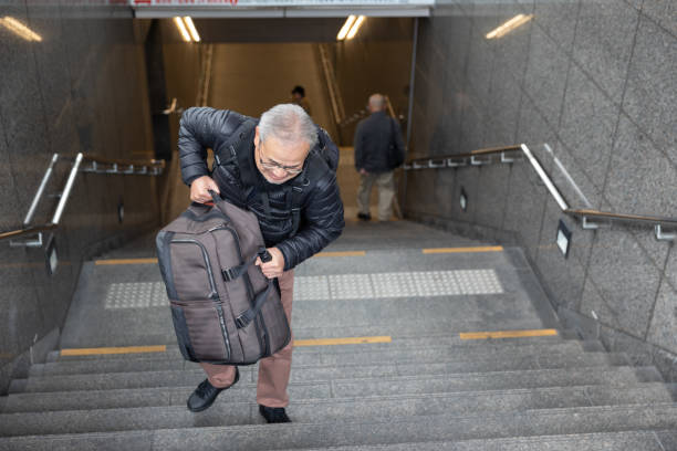 istock Senior man walking up the stairs with suitcase 1213731782
