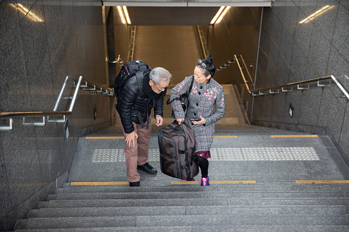 Woman helping senior man to carry suitcase