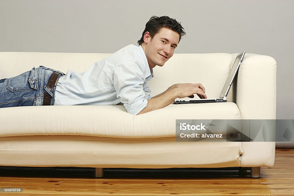 Navigazione Web sul divano con un sorriso - Foto stock royalty-free di Divano