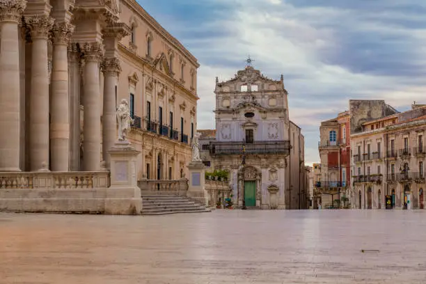 Cityscape of the main square of Ortygia island and the church of Santa Lucia in Badia at cloudy sunrise in province of Syracuse in Sicily