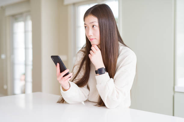 istock Beautiful Asian woman using smartphone serious face thinking about question, very confused idea 1213740420