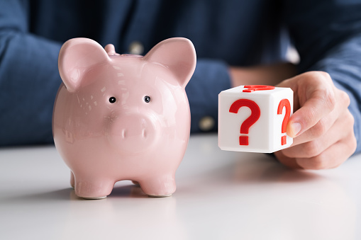Man Holding Question Mark Next To Piggy Bank. Money Saving And Investment Strategies Concept