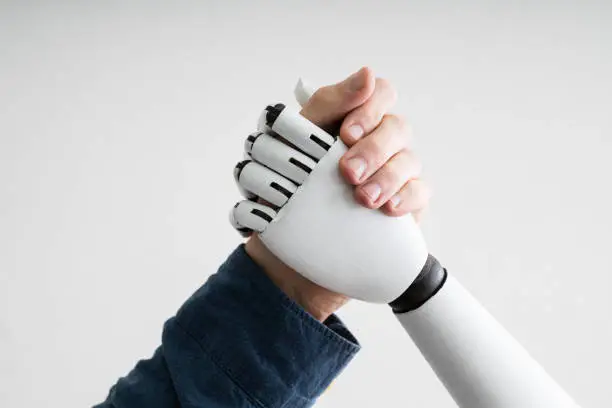 Close-up Of Businessperson Shaking Hands With Robot