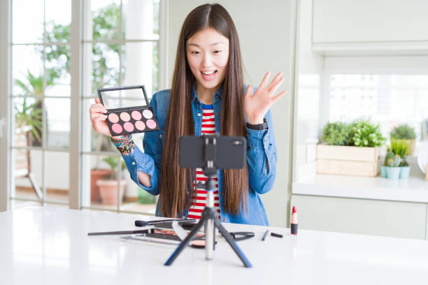 istock Beautiful Asian influencer woman recording make up tutorial using smartphone camera very happy and excited, winner expression celebrating victory screaming with big smile and raised hands 1213742689