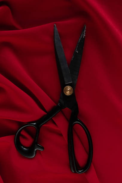 istock Red fabric on the table with black professional scissors 1213743126
