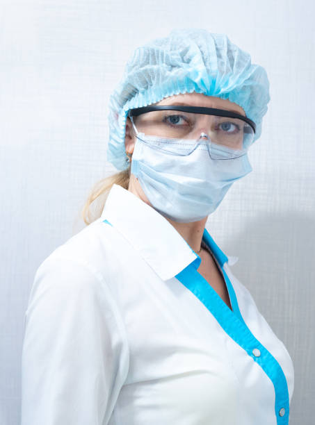 istock nurse in mask, hat and goggles on a light background 1213743292