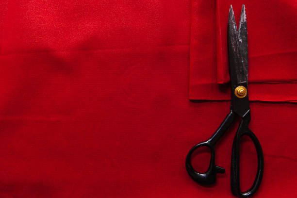 istock Red fabric on the table with black professional scissors 1213743813