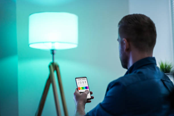 istock Human Hand Adjusting Electric Light Through Mobile Phone 1213744553