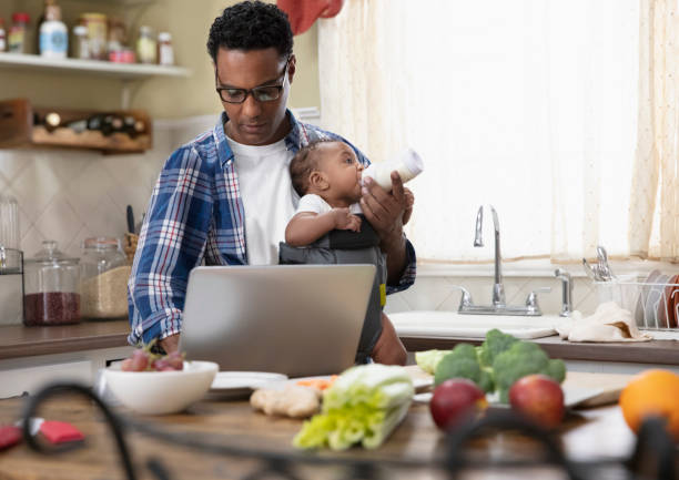 Father working from home holding baby stock photo