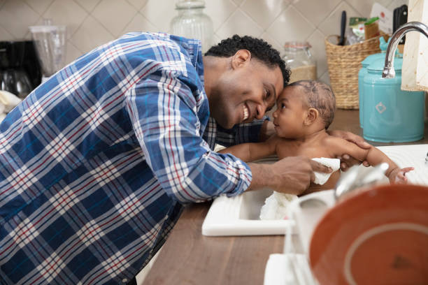 istock Father giving his baby a bath in the kitchen sink 1213744702