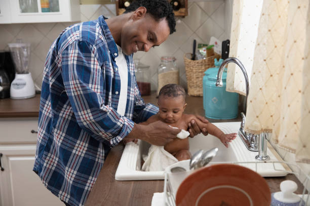 istock Father giving his baby a bath in the kitchen sink 1213744735