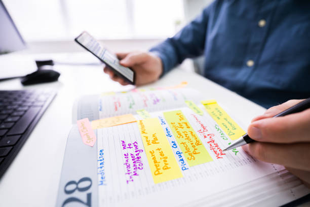 istock Businessman Holding Cellphone Writing Schedule In Diary With Pen 1213744749