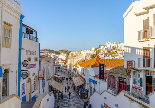 This pic shows Albufeira old town in Portugal at day time. Old town cobbledstoned street with shops and some tourists can be seen in the pic. The pic is taken in day time in january 2020.