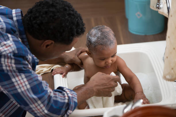 istock Father giving his baby a bath in the kitchen sink 1213744876