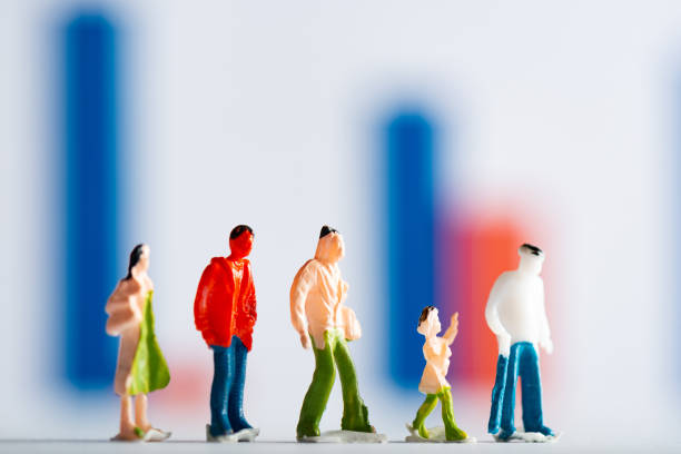 istock Selective focus of row of people figures on white surface with graphs at background, concept of equality 1213745143