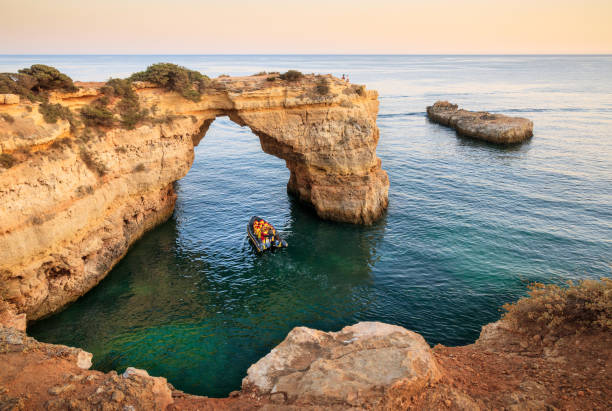 Albandeira Arch with a tour boat passing underneath in Algarve, Portugal. stock photo