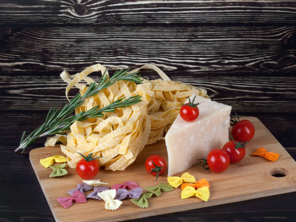 suchy włoski makaron fettuccini i farfalle z pomidorami, serem i rozmarynem - bow tie pasta italian cuisine bow heap zdjęcia i obrazy z banku zdjęć
