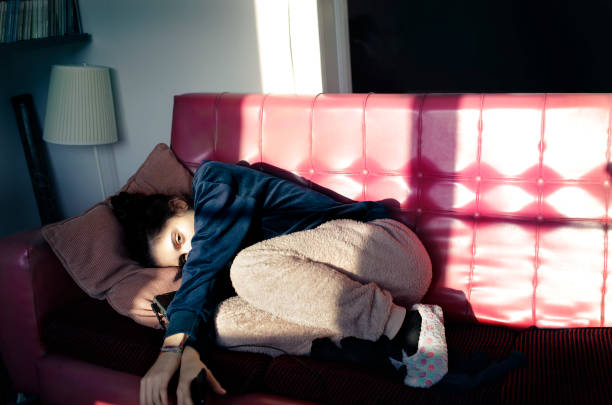 adolescente deitada em um sofá vermelho - solitary confinement - fotografias e filmes do acervo
