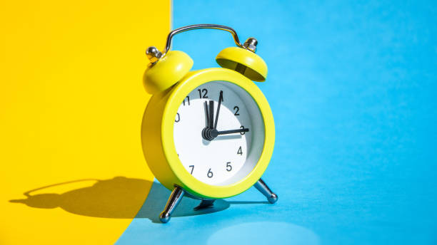 istock Yellow vintage alarm clock on a blue and yellow background with selective focus, copy space for text 1213753466