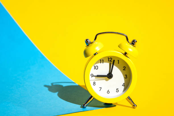 istock Yellow vintage alarm clock on a blue and yellow background with selective focus, copy space for text 1213753608