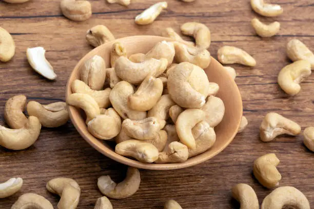 Cashew Nuts in a wooden bowl on brown background