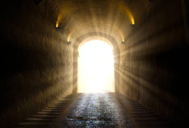 une lumière rougeoyante jaune vif perçant à travers au bout d’un tunnel foncé - apercevoir le bout du tunnel photos et images de collection