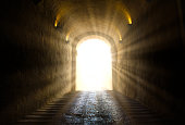 istock A bright yellow glowing light breaking through at the end of a dark tunnel 1213757920
