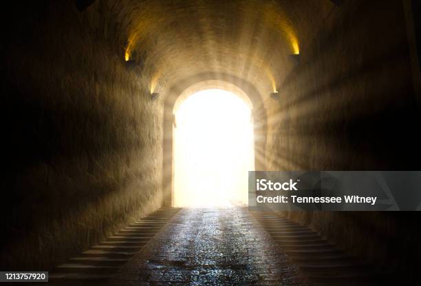 A Bright Yellow Glowing Light Breaking Through At The End Of A Dark Tunnel Stock Photo - Download Image Now