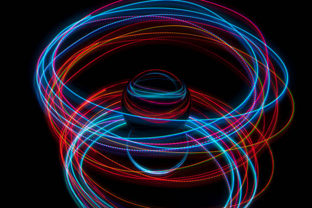 Abstract light painting circling around a crystal ball on a black background.