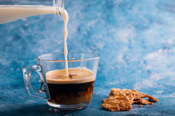 istock milk pouring to coffee on blue background 1213760382